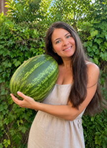 Naima mit einer Wassermelone im Garten