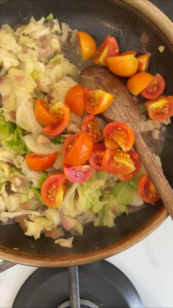 Wirsing mit kleinen Tomaten in der Pfanne andünsten