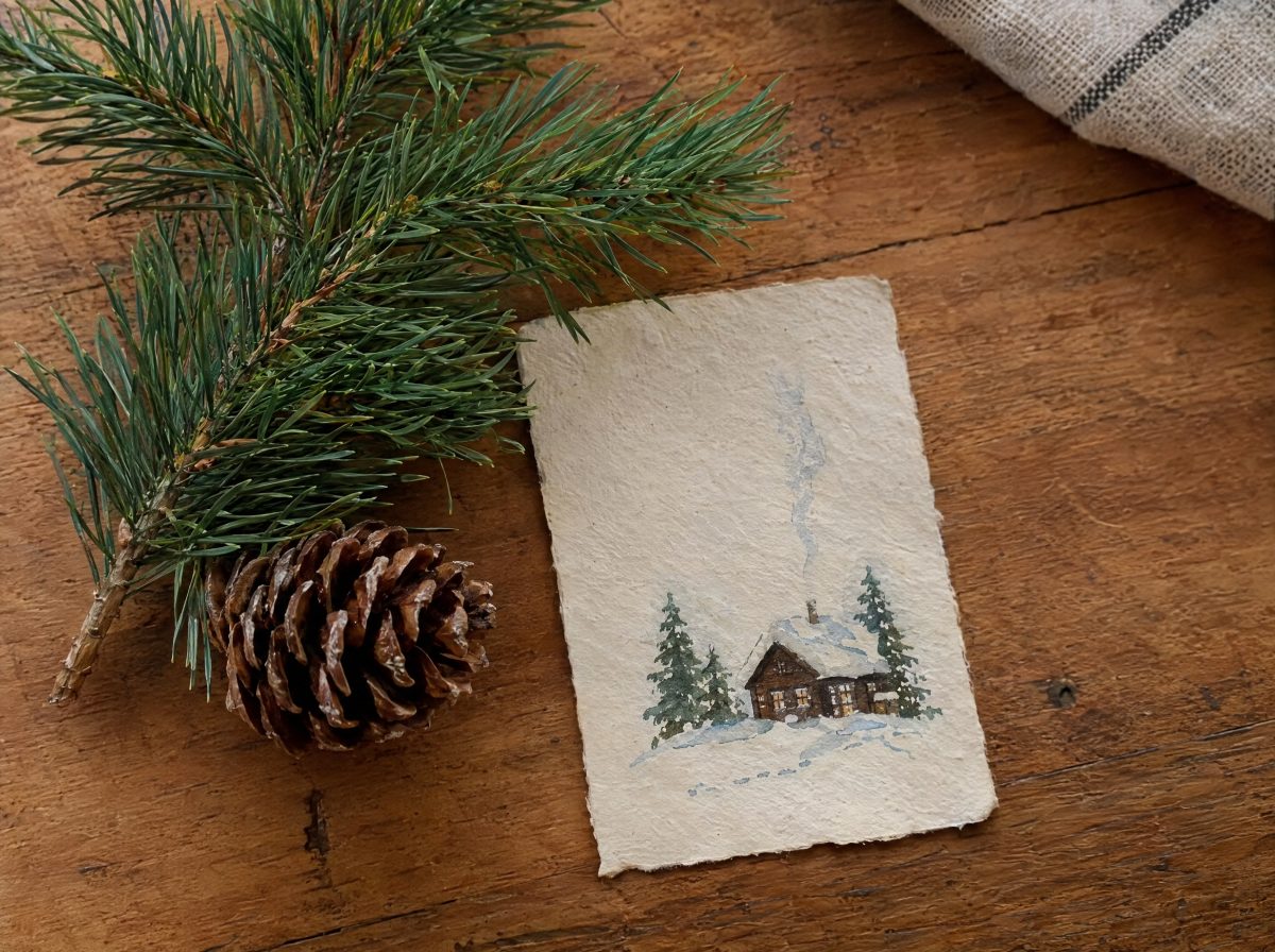 Kleine handgeschriebene Aufgabenkarte mit Winterzeichnung neben einem Tannenzweig