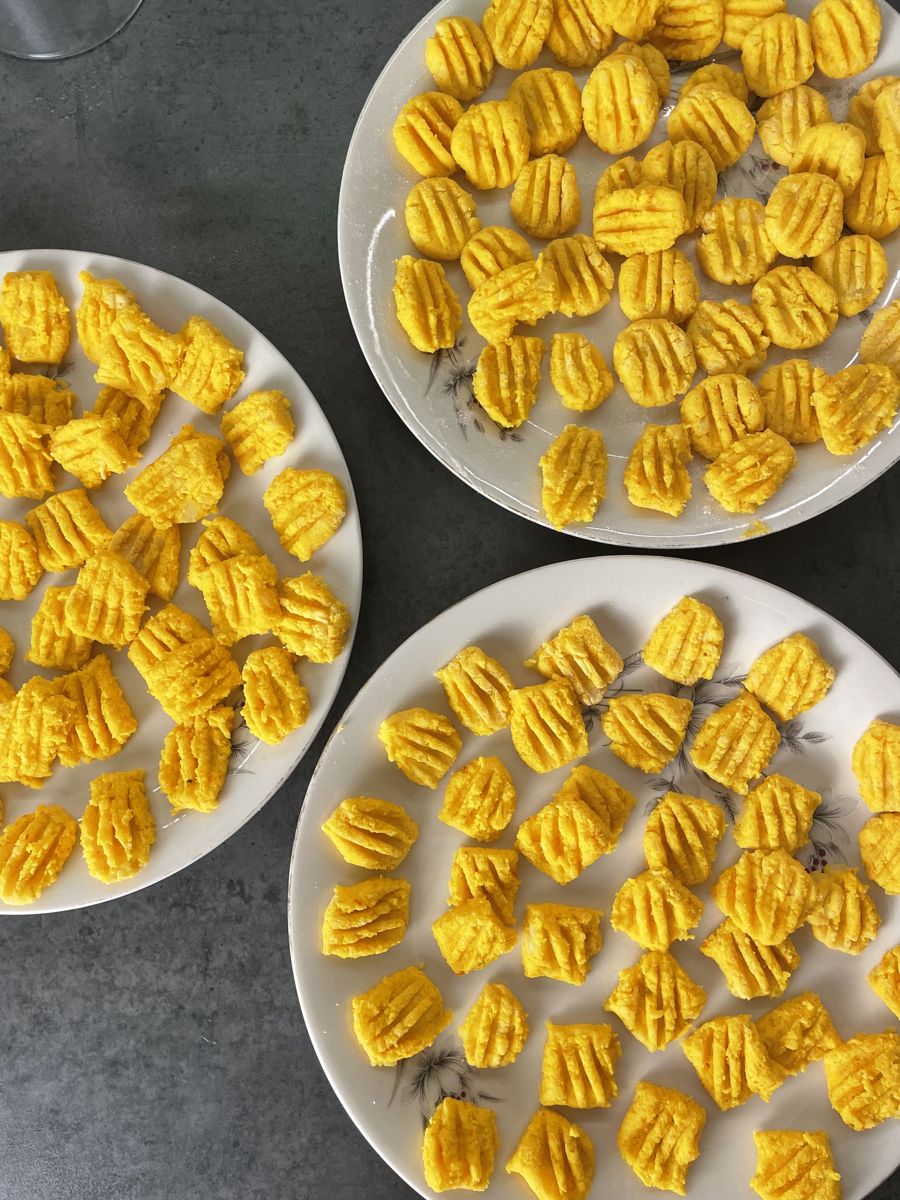 Rohe vegane Kürbis-Gnocchi mit Gabelrillen auf drei Tellern