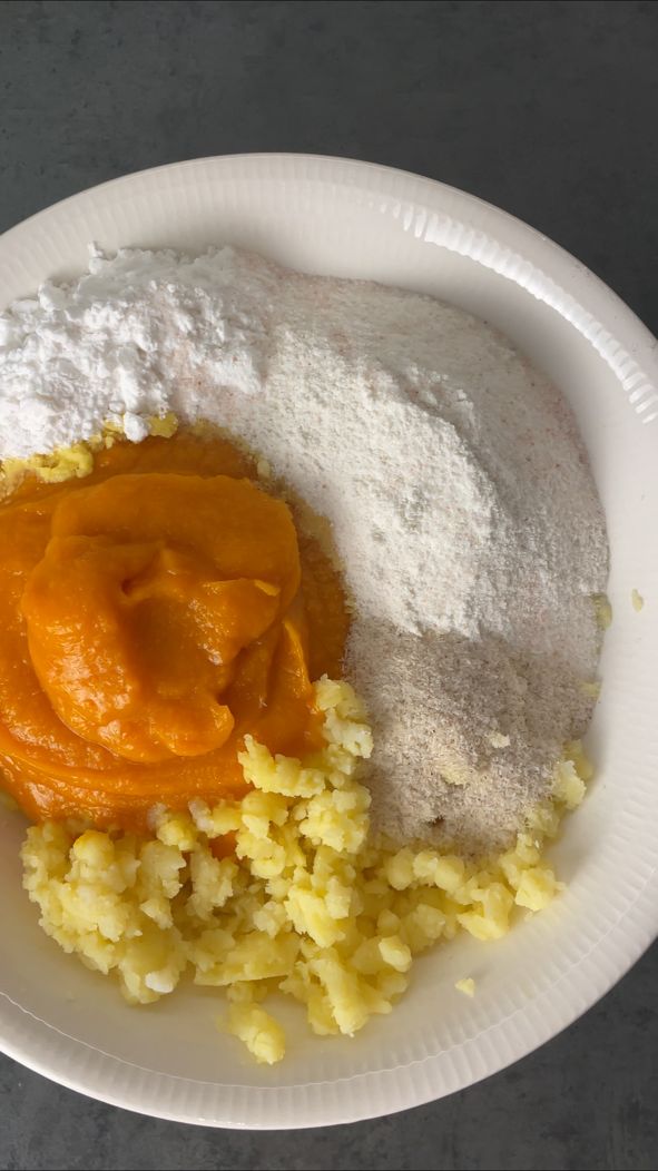 Zutaten für vegane Kürbis-Gnocchi auf einem Teller: Kürbismus, zerdrückte Kartoffeln, Reismehl und Kartoffelstärke