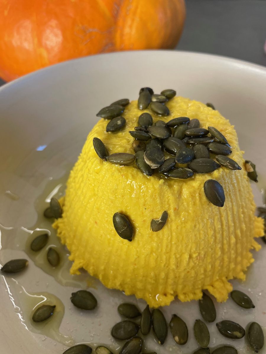 Veganer Kürbis-Ricotta von oben mit gerösteten Kürbiskernen und Olivenöl, daneben ein Hokkaido-Kürbis