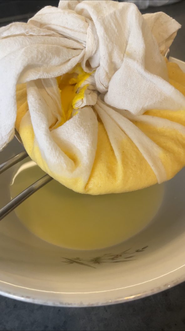Veganer Ricotta tropft im zugebundenen Baumwolltuch über einer Schüssel ab